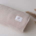Close-up of a beige knitted baby blanket with Snuggle Threads label