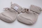 Beige knitted baby booties with ribbed cuffs and tie detail