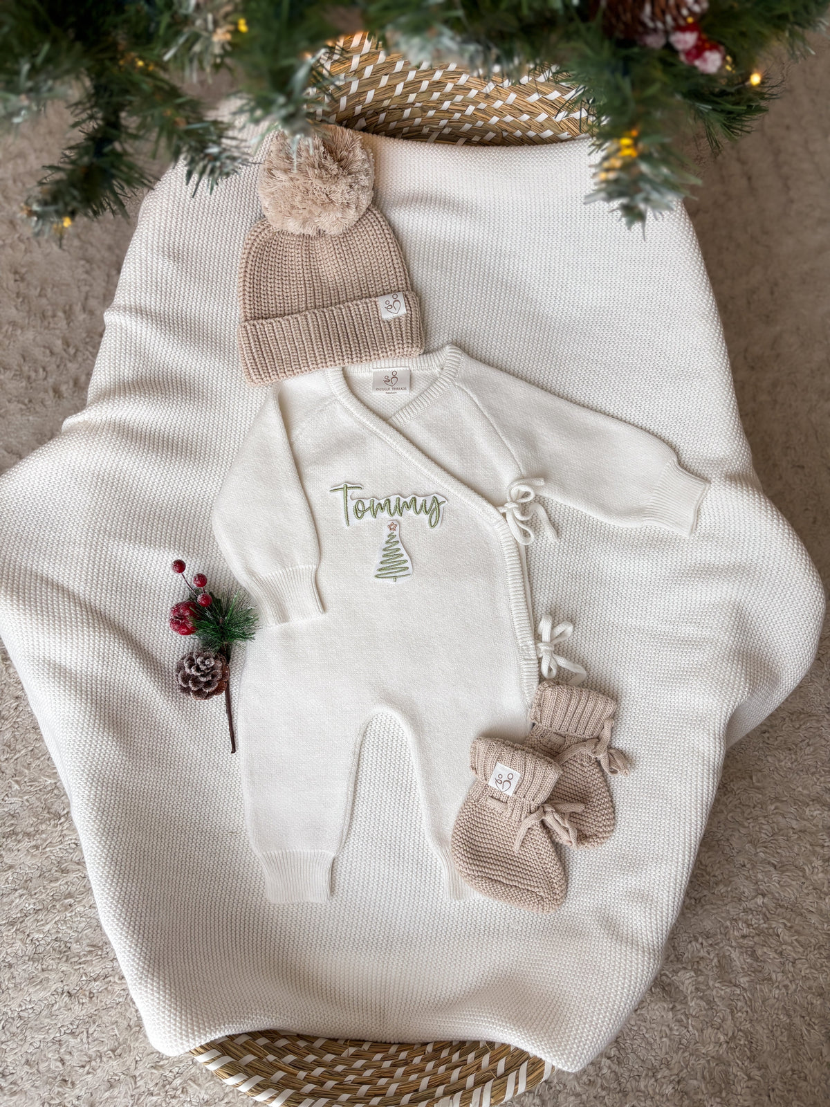 Personalised ivory knitted Christmas baby wrap romper with custom name and green Christmas tree embroidery, beige hat and booties