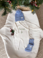 Personalised ivory knitted Christmas baby wrap romper with custom name and green Christmas tree embroidery, blue knitted hat and booties