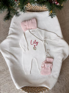 Personalised ivory knitted Christmas baby wrap romper with custom name and mistletoe embroidery, light pink knitted bow and booties