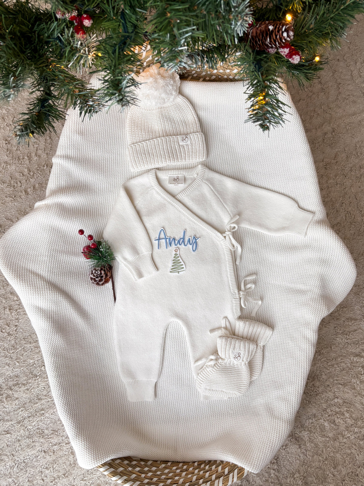 Personalised ivory knitted Christmas baby wrap romper with custom name and Christmas tree embroidery, matching ivory hat and booties