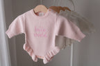 Pink knitted baby romper available for personalised embroidery hanging on a wooden hanger