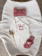 Personalised She's Here baby wrap romper with dusty pink knitted baby booties and headbow